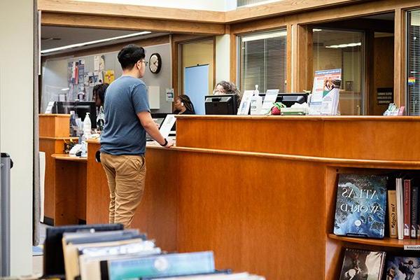 Student at library desk checking out book